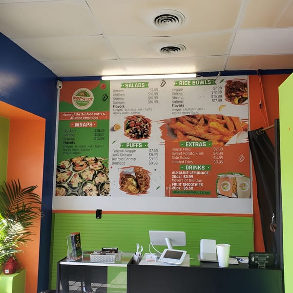 A menu board for WRAP-A-LOT Fresh Express, featuring salads, wraps, rice bowls, puffs, extras, and drinks.
