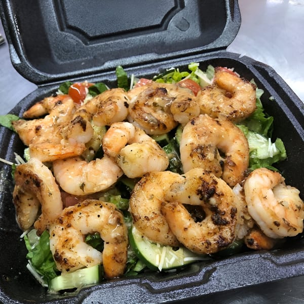 A close-up of a WRAP - A - LOT Fresh Express shrimp salad with lettuce, tomatoes, and cucumbers.